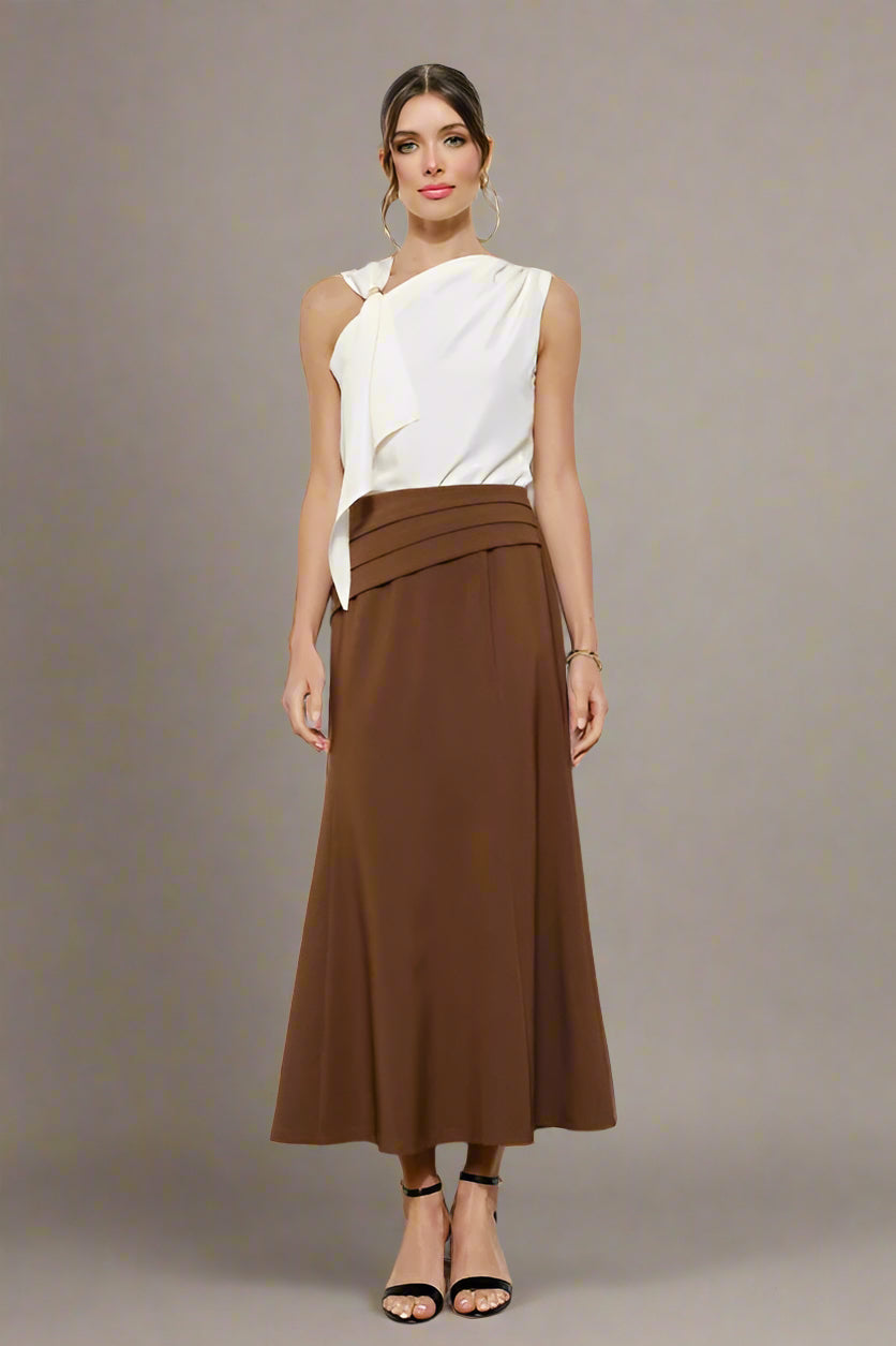 Woman wearing a white top and brown skirt on a plain background