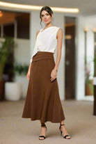 


Woman wearing a white top and brown skirt against a white background