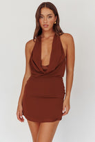 Woman wearing a brown halter neck dress on a white background