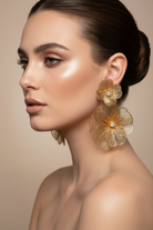 Pair of gold floral earrings with diamond centers on a white background