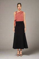 Woman wearing a pink top and black skirt on a white background